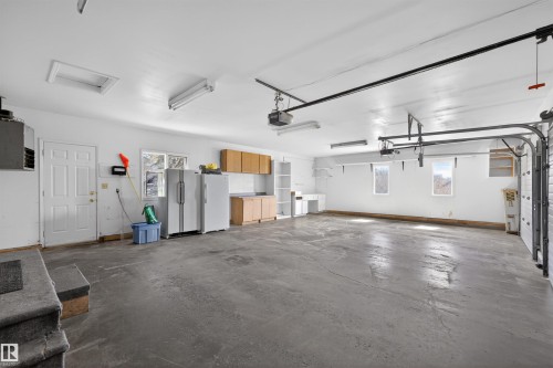 Spacious garage featuring a concrete floor, multiple windows, built-in cabinetry, and overhead lighting - 19403 Fort Road, Edmonton, AB - Indoor Photo Showing Garage