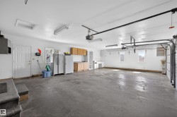 Spacious garage featuring a concrete floor, multiple windows, built-in cabinetry, and overhead lighting - 
