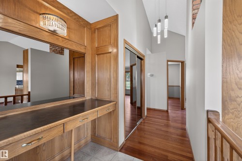 Custom oak cabinetry with integrated countertop and storage drawers, illuminated by a decorative wall sconce - 19403 Fort Road, Edmonton, AB - Indoor Photo Showing Other Room