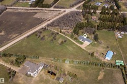 Aerial perspective showcasing a single-story residence with a gray roof and light-colored siding, positioned on a large lot - 