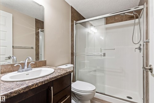 Bathroom featuring a dark wood-finish vanity with a speckled countertop, undermount sink, and chrome fixtures - 316 10520 56 Avenue Nw, Edmonton, AB - Indoor Photo Showing Bathroom