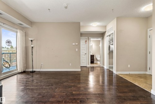 Spacious interior featuring dark wood-finish flooring, a sliding glass door to a balcony, light neutral wall paint, and recessed ceiling lighting - 316 10520 56 Avenue Nw, Edmonton, AB - Indoor Photo Showing Other Room