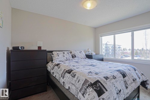 Master Bedroom featuring neutral wall paint, textured ceiling, a large window with white trim, and carpet flooring - 1622 33A Street Nw, Edmonton, AB - Indoor Photo Showing Bedroom
