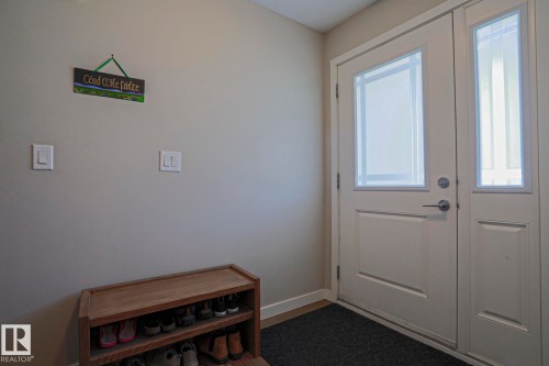 Entryway featuring a white paneled door with frosted glass insert, coordinating frosted glass sidelight, and light-toned wall paint - 1622 33A Street Nw, Edmonton, AB - Indoor Photo Showing Other Room