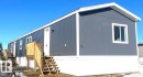 Contemporary exterior featuring gray vertical siding, white trim, and a white entry door - 109-4819 51 Ave, Millet, AB  - Outdoor 