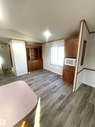 Spacious interior featuring wood-finish flooring, a built-in wood hutch, additional built-in wood cabinetry, and ample natural light from the window - 109-4819 51 Ave, Millet, AB - Indoor