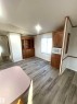 Spacious interior featuring wood-finish flooring, a built-in wood hutch, additional built-in wood cabinetry, and ample natural light from the window - 109-4819 51 Ave, Millet, AB  - Indoor 