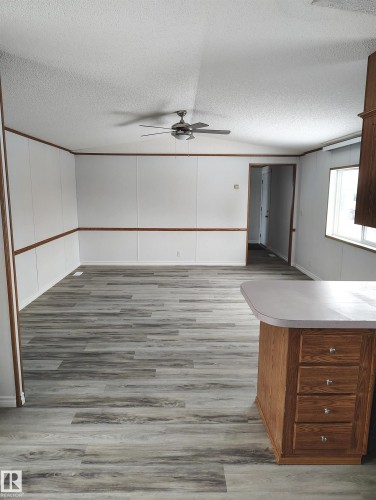Spacious room featuring wood-finish flooring, white paneling with wood trim, and a ceiling fan - 109-4819 51 Ave, Millet, AB - Indoor Photo Showing Other Room
