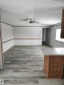 Spacious room featuring wood-finish flooring, white paneling with wood trim, and a ceiling fan - 109-4819 51 Ave, Millet, AB  - Indoor Photo Showing Other Room 
