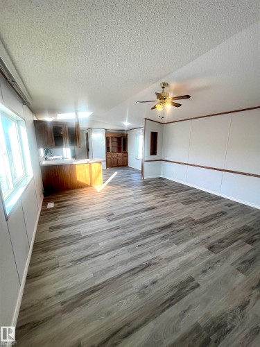 Spacious interior featuring wood-finish flooring, white paneling, and a ceiling fan - 109-4819 51 Ave, Millet, AB - Indoor Photo Showing Other Room
