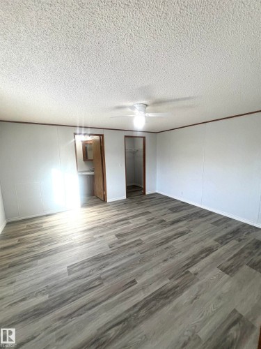 Spacious room featuring wood-finish flooring, white paneled walls, and a ceiling fan - 109-4819 51 Ave, Millet, AB - Indoor Photo Showing Other Room