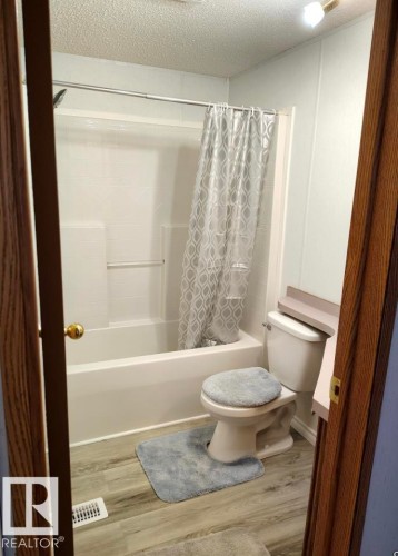 Bathroom with an integrated tub and shower combination featuring a white surround - 109-4819 51 Ave, Millet, AB - Indoor Photo Showing Bathroom