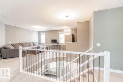 Upper-level landing featuring open baluster railing and carpeted flooring - 