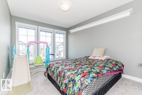 Bedroom featuring three large windows with white trim, light gray painted walls, and light-colored carpeting - 9748 205 Street, Edmonton, AB - Indoor Photo Showing Bedroom