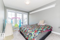 Bedroom featuring three large windows with white trim, light gray painted walls, and light-colored carpeting - 