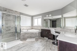 Spacious bathroom featuring large format tile flooring and a glass-enclosed shower - 
