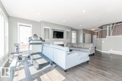 Spacious open-concept room featuring wood-finish flooring, recessed lighting, and a built-in media niche with a fireplace - 