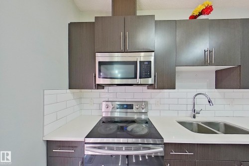 Modern kitchen featuring dark wood-finish cabinetry, white subway tile backsplash, and light-toned countertops - 1221 27 Street, Edmonton, AB - Indoor Photo Showing Kitchen With Double Sink