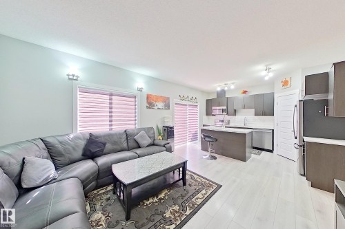 Open-concept living area featuring a kitchen with dark cabinetry, stainless steel appliances, and a central island - 1221 27 Street, Edmonton, AB - Indoor Photo Showing Living Room