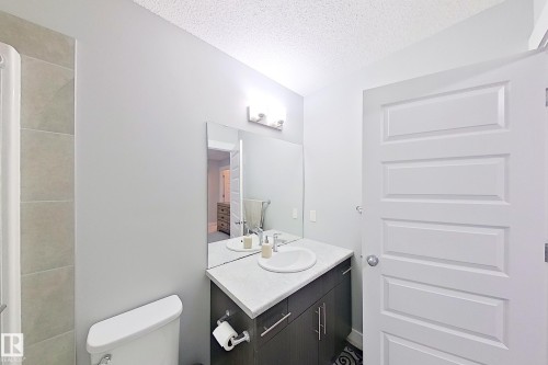 Bathroom featuring a dark wood-finish vanity with a white countertop and integrated sink, a rectangular mirror, and a three-light vanity fixture - 1221 27 Street, Edmonton, AB - Indoor Photo Showing Bathroom