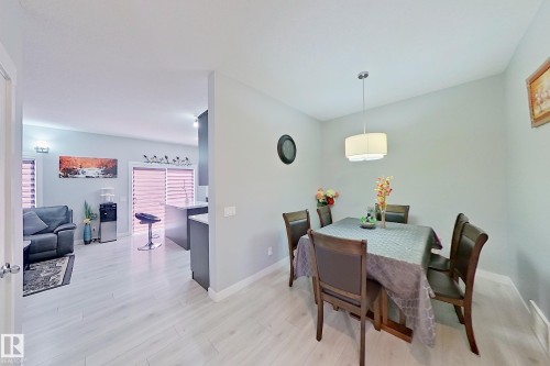 Open-concept living area featuring light wood-finish flooring, recessed lighting, a modern drum pendant light fixture, and a kitchen island with seating - 1221 27 Street, Edmonton, AB - Indoor Photo Showing Dining Room
