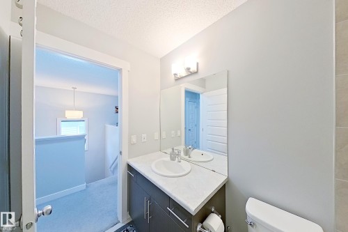 Bathroom vanity featuring a single basin, light-colored countertop, and dark wood-finish cabinetry with modern hardware - 1221 27 Street, Edmonton, AB - Indoor Photo Showing Bathroom