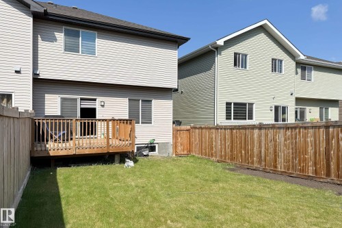 Expansive backyard featuring a manicured lawn, full privacy fencing, a wood deck, and siding exterior - 1221 27 Street, Edmonton, AB - Outdoor With Exterior