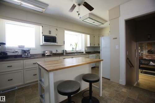 Kitchen featuring a central island with a wood-finish countertop, light-toned cabinetry, and tile flooring - 12137 50 Street, Edmonton, AB - Indoor Photo Showing Kitchen With Double Sink