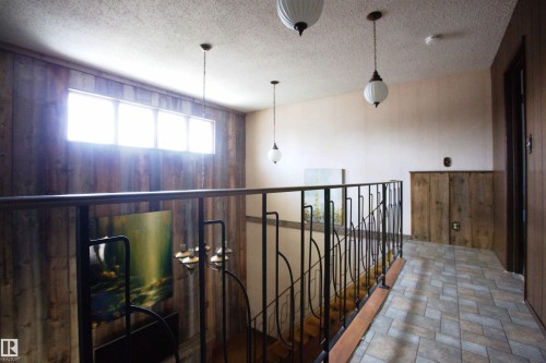 Upper-level hallway featuring patterned tile flooring, wood-paneled walls, and multiple pendant light fixtures - 12137 50 Street, Edmonton, AB - Indoor Photo Showing Other Room