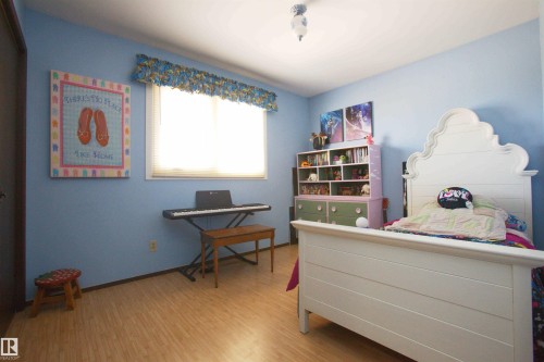 Room with wood-finish flooring, a single window with blinds, and light blue walls - 12137 50 Street, Edmonton, AB - Indoor Photo Showing Bedroom