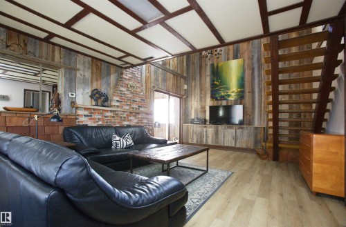 Living area featuring wood-finish flooring, exposed brick, wood paneling, and a wood staircase - 12137 50 Street, Edmonton, AB - Indoor