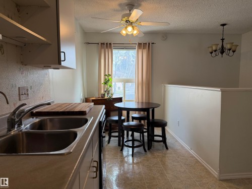 Kitchen featuring a double basin stainless steel sink, light-colored countertops, and white upper cabinetry - 1875 Mill Woods Road E, Edmonton, AB - Indoor Photo Showing Kitchen With Double Sink