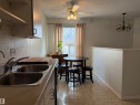 Kitchen featuring a double basin stainless steel sink, light-colored countertops, and white upper cabinetry - 1875 Mill Woods Road E, Edmonton, AB  - Indoor Photo Showing Kitchen With Double Sink 