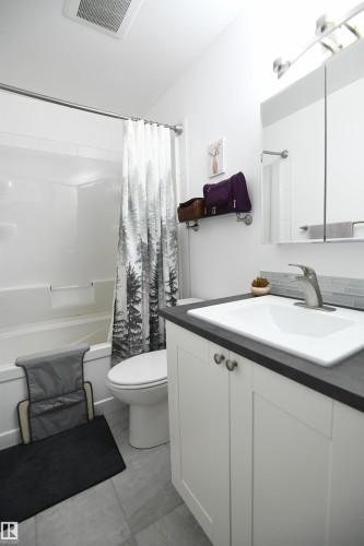 Like the kitchen, both bathrooms in the home have received a bright and contemporary renovation.  The white cabinetry, new fixtures, solid surface counters, and tile accents look great - 5823 Riverbend Road, Edmonton, AB - Indoor Photo Showing Bathroom