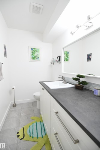 Like the kitchen, both bathrooms in the home have received a bright and contemporary renovation.  The white cabinetry, new fixtures, solid surface counters, and tile accents look great.  This main floor bathroom even has additional counter space - 5823 Riverbend Road, Edmonton, AB - Indoor Photo Showing Bathroom