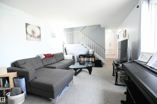 The open railings that lead upstairs to the bedroom level give an open feel to the large living room, with great furniture placement options.  The kitchen and large dining area are just around the corner to the right - 5823 Riverbend Road, Edmonton, AB - Indoor