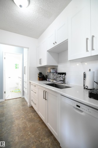 Recent renovations to both bathrooms in the home, as well as the kitchen, are standouts here.  White shaker cabinetry, solid surface counters, undermount sink, tile backsplash, a full sized pantry and more - 5823 Riverbend Road, Edmonton, AB - Indoor Photo Showing Kitchen