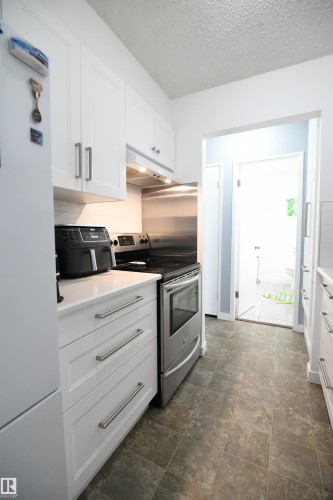 Recent renovations to both bathrooms in the home, as well as the kitchen, are standouts here.  White shaker cabinetry, solid surface counters, undermount sink, tile backsplash, a full sized pantry and more - 5823 Riverbend Road, Edmonton, AB - Indoor Photo Showing Kitchen