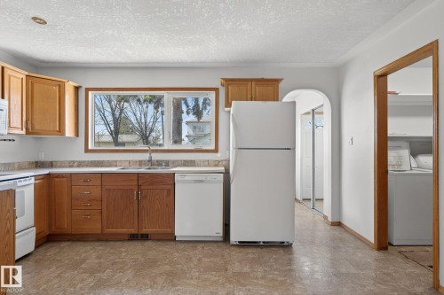 Kitchen featuring wood cabinetry, laminate countertops, a double basin sink, and a white appliance package - 13412 108 Street, Edmonton, AB - Indoor Photo Showing Kitchen
