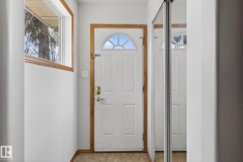 Entryway featuring a white paneled door with an arched glass insert, natural wood trim, and a full-length mirrored closet door - 13412 108 Street, Edmonton, AB - Indoor Photo Showing Other Room