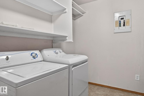 Dedicated laundry area featuring white appliances, a wall-mounted electrical panel, and multiple white storage shelves - 13412 108 Street, Edmonton, AB - Indoor Photo Showing Laundry Room