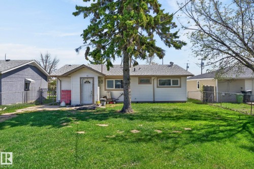 Front exterior featuring white horizontal siding, a covered entry, and a prominent evergreen tree - 13412 108 Street, Edmonton, AB - Outdoor