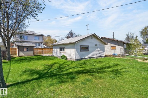 Expansive lawn area featuring a detached garage with vinyl siding and a separate storage shed - 13412 108 Street, Edmonton, AB - Outdoor