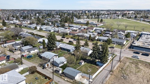 Aerial perspective showcasing a residential neighborhood with single-story homes, mature trees, paved streets, and undeveloped land - 13412 108 Street, Edmonton, AB - Outdoor With View