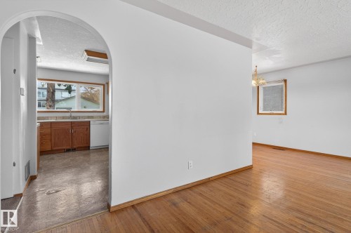 Archway entry leading to the kitchen featuring wood cabinetry, stone-look countertops, and a double basin sink - 13412 108 Street, Edmonton, AB - Indoor Photo Showing Other Room