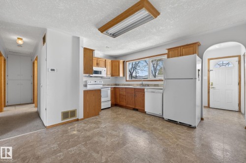 Kitchen featuring wood cabinetry, white appliances, and a window above the sink - 13412 108 Street, Edmonton, AB - Indoor Photo Showing Kitchen
