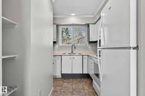 Kitchen featuring white cabinetry, light-toned countertops, a stainless steel sink with a high-arc faucet, and an integrated white appliance package including a refrigerator, range, and dishwasher - 18 17409 95 Street, Edmonton, AB - Indoor Photo Showing Kitchen With Double Sink