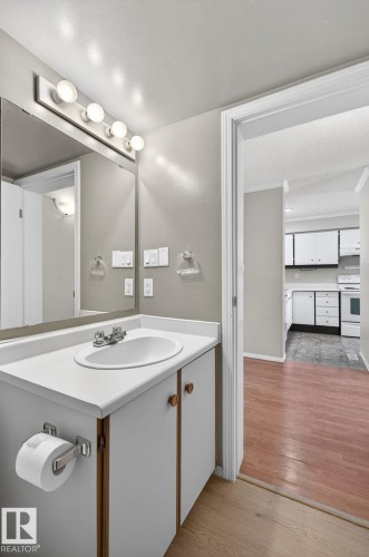 Bathroom vanity with integrated sink, chrome faucet, and overhead bar lighting - 18 17409 95 Street, Edmonton, AB - Indoor Photo Showing Bathroom