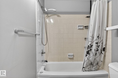 Bathtub and shower combination featuring white tile surround, chrome fixtures, and a handheld showerhead - 18 17409 95 Street, Edmonton, AB - Indoor Photo Showing Bathroom