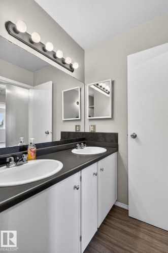 Dual vanity featuring white cabinetry and dark countertops - 18 17409 95 Street, Edmonton, AB - Indoor Photo Showing Bathroom